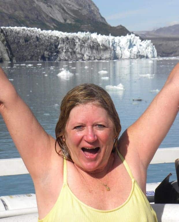 Happy small ship traveler excited after jumping in the cold waters of Alaska with a tidewater glacier in the background.
