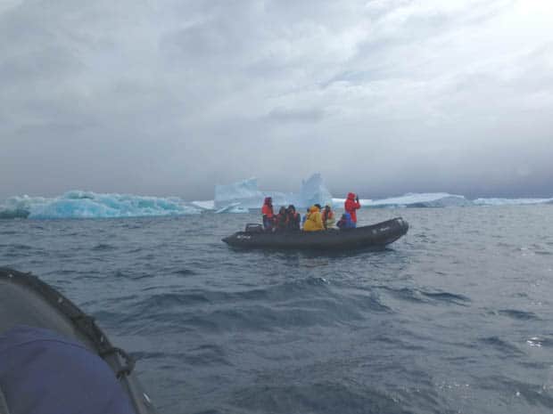 Small cruise ship guests on a skiff near icebergs in Antarctica. 