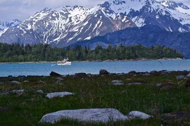 The small ship sea wolf cruising past tall mountains in Alaska. 