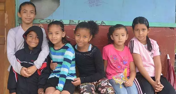 Local school children smiling in front of the Laguna de Tortuguero School in Costa Rica. 