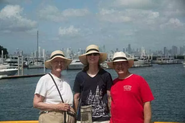 three adventure travelers wearing hats stand in the harbor in panama city on a partly cloudy day