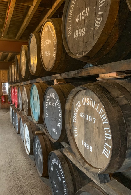 Three levels of wooden whiskey casks with the year it had started aging printed on the side, seen at a whiskey distillery on the Classic Scotland Barge Cruise.