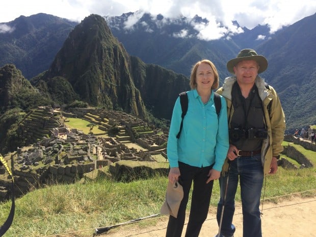 Happy couple on a hiking trail overlooking the ancient ruin of Machu Picchu in Peru.