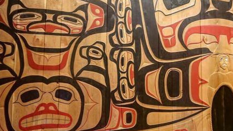 Wooden Tlingit Native Alaska Haida house with Alaskan cultural artwork in red & black on the exterior.
