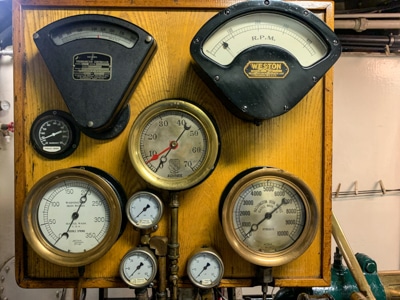 Inside the engine room engine room aboard small ship catalyst, copper and black machinery faceplates and gauges for the steam engine.