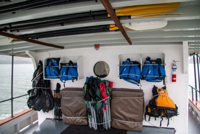 A covered deck aboard Alaska small ship catalyst, where adventure activity items like kayak paddles and lift jackets are stored.