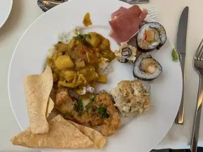 Dinner plate filled with a selection of sushi, curry with rice and other menu items served aboard Greg Mortimer ship.