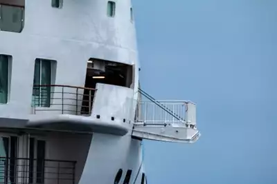 The observation deck has been lowered from the side of Greg Mortimer ship and extends over the ocean suspended by hydraulic arms.