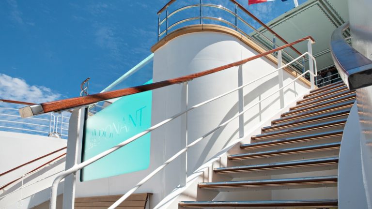 Teak wood staircase leads up to the edge of a turquoise infinity pool aboard Le Bellot French ship.