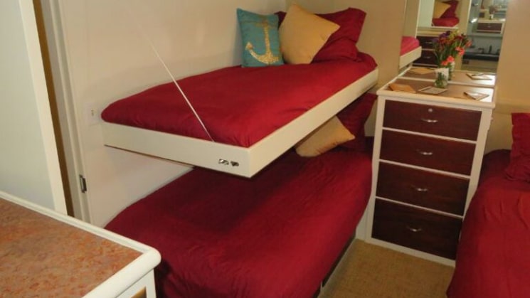 3 twin beds with dark red bedding, 1 as a pull-down berth, comprise a cabin aboard the Sea Star yacht.