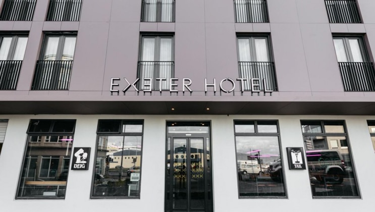 Exterior of entryway to Exeter Hotel in Reykjavik, Iceland, with modern gray steel & stone plus tall windows.