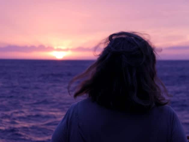 Person watching the sunset from a small ship cruise in Hawaii. 