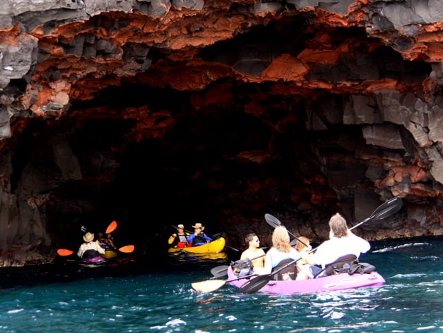 Guests from a small ship cruise in Hawaii kayak into a cave. 