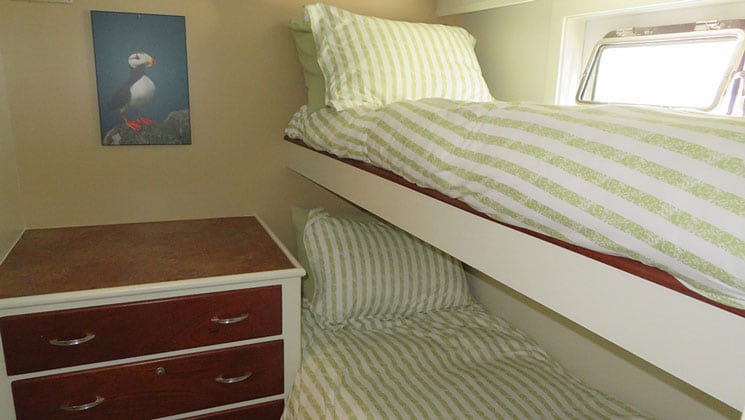 Puffin cabin on AK yacht Sea Star, with one lower and one upper single bed, each with green & white striped bedding & white walls.