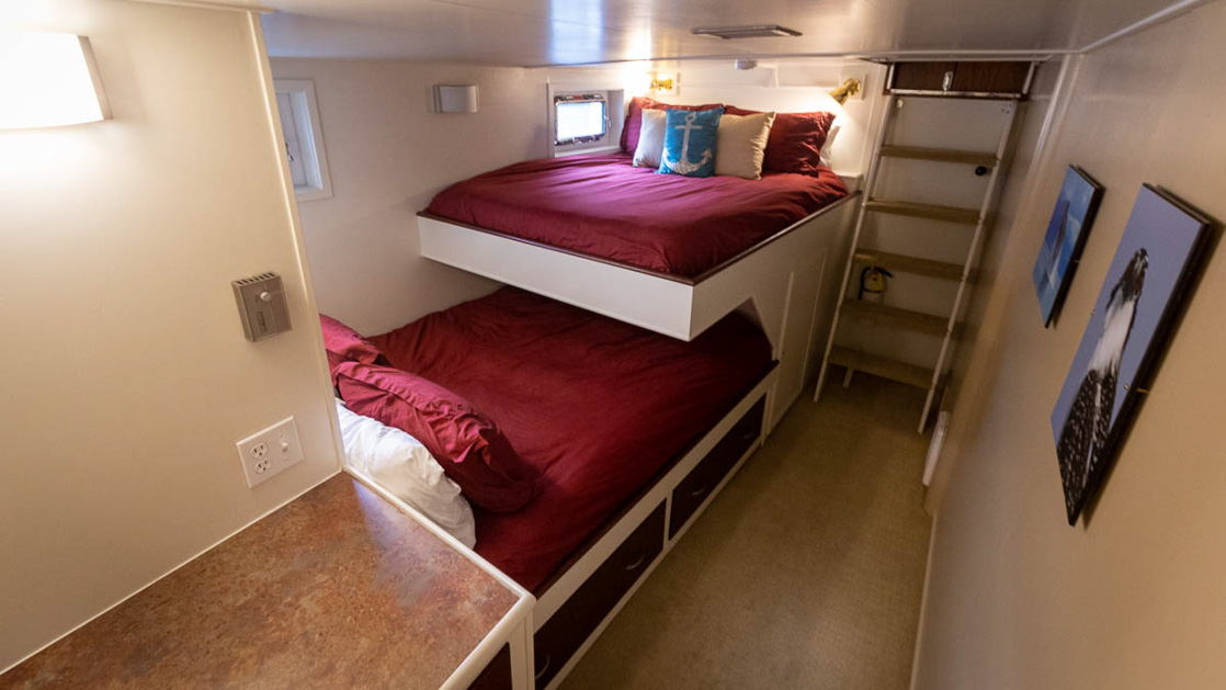 two full sized beds with accents allowing for quad occupancy with two windows and a desk on this cruise aboard the Sea Star