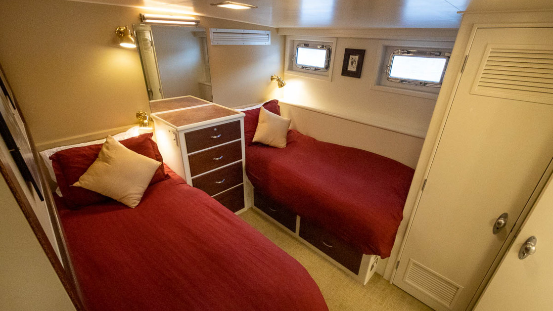 a double occupancy cabin featuring two twin beds two portholes and a mulidrawer nightstand on this cruise aboard the Sea Star