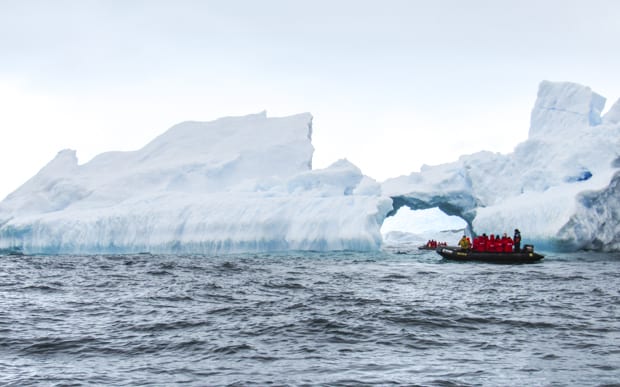 Passengers on a skiff excursion from a small ship cruise ride up close to large icebergs. 