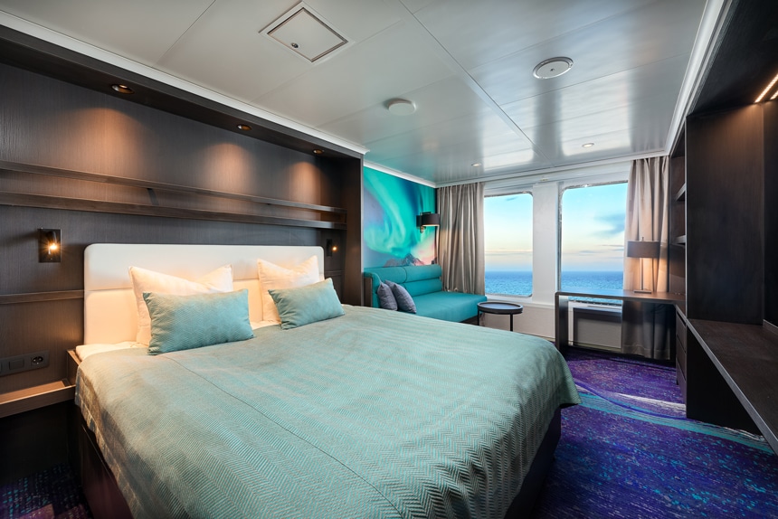 Antarctica ship cabin rendering showing two large view windows, seating area, large bed and TV.