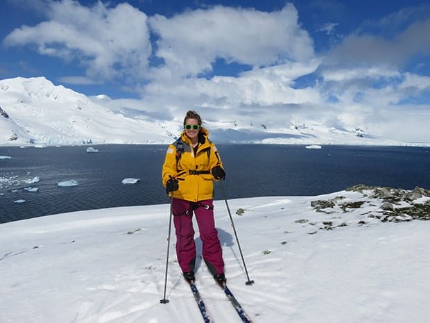 Girl smiling in yellow jacket cross country skiing in Antarctica after reaching 7 continents