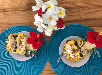 Cuisine aboard Belize sailboat charter, a cut open half yellow pineapple filled with yogurt, granola and other cut fruit.
