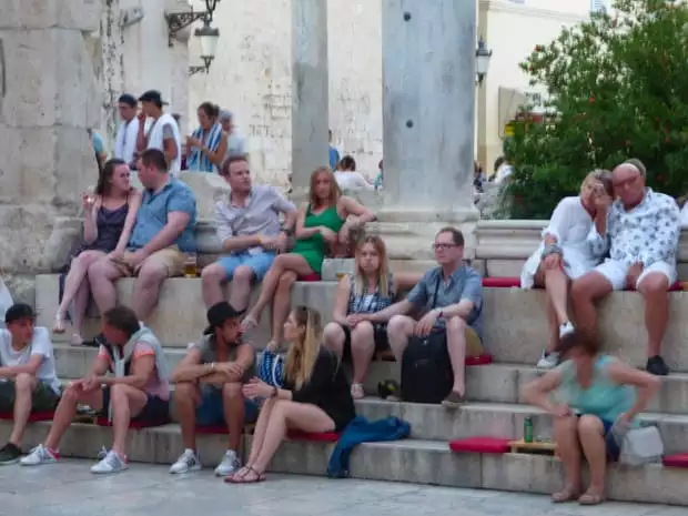 Tourists sitting on steps in Dubrovnik.