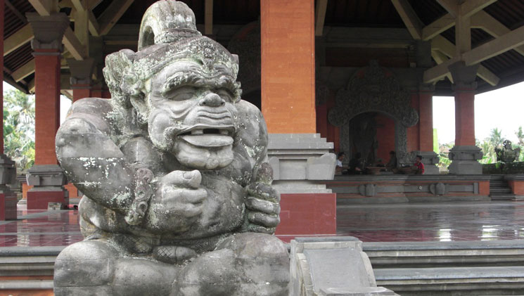 Stone statue of an Indonesian God sits at the entryway to an open-air mosque, seen on National Geographic Indonesia Cruises.