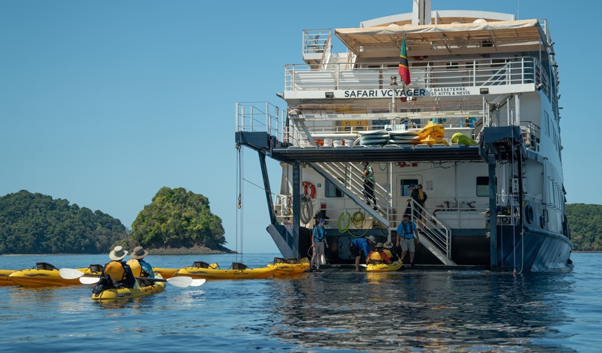 The crew of the Safari Voyager, a small expedition ship, assist guests from a boat platform into the water in their Kayaks for an activity, 