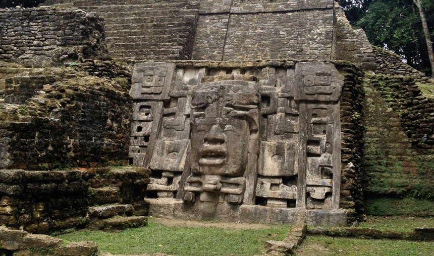 The Mask Temple, a Maya temple and civilization structure at the archaeological site in Belize with limestone walls featuring a mask with facial features.  