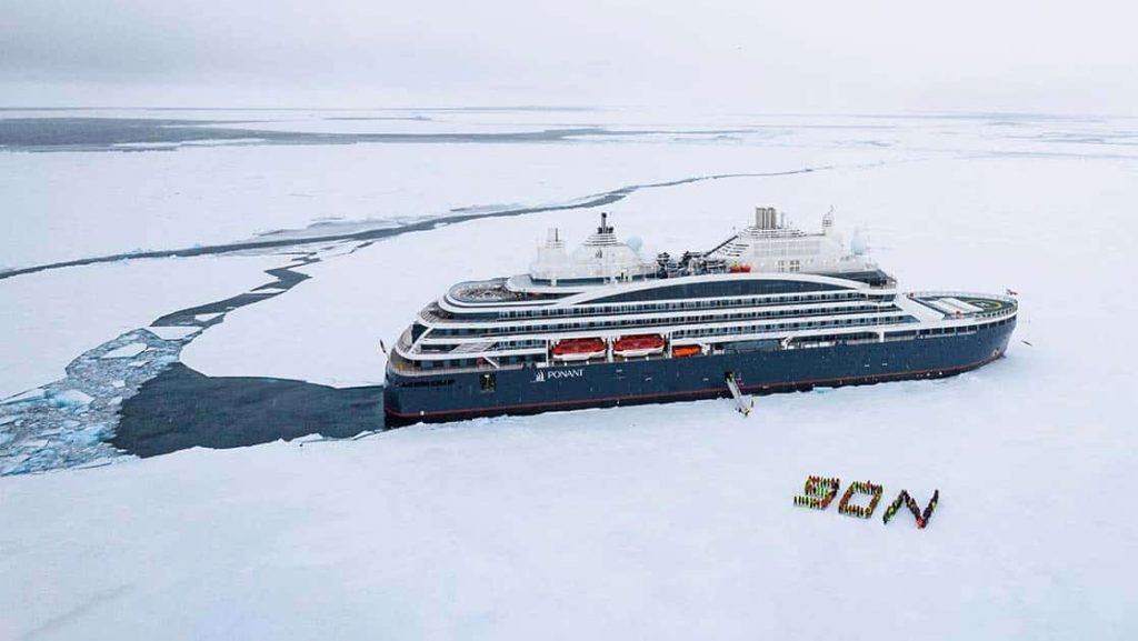 Aerial view of Le Commandant Charcot polar expedition ship stopped in the ice with guests ashore during a Ross Sea expedition.