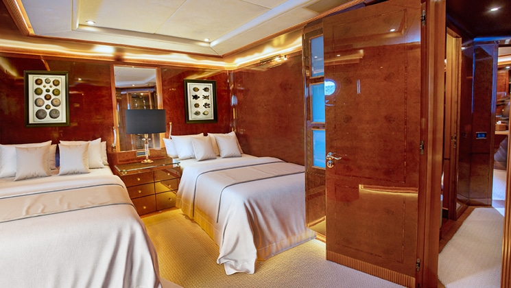 Category IV cabin on Aqua Mare Galapagos superyacht with 2 twin beds, wooden walls, accent lights & nautical theme.
