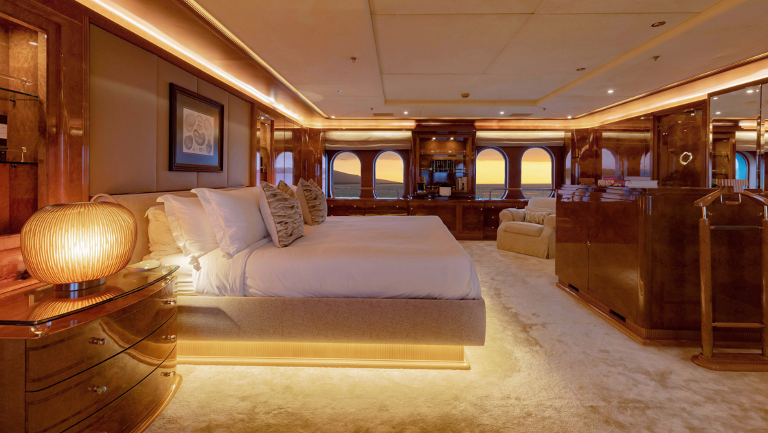 Owner's Suite bedroom on Aqua Mare Galapagos superyacht, with double bed, ample floorspace, accent lights & veneer furniture.