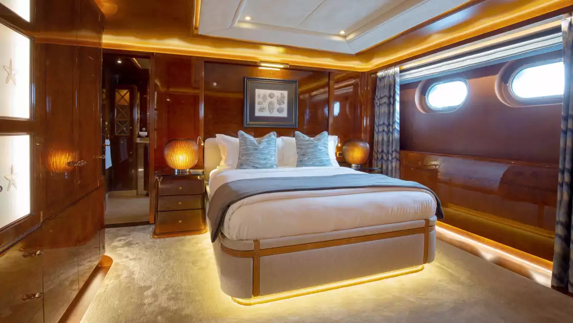 Category III cabin on Aqua Mare Galapagos superyacht with queen bed, wooden walls, portholes, accent lights & nautical theme.