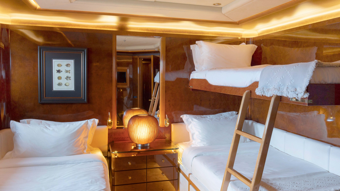 Category IV cabin on Aqua Mare Galapagos superyacht with 2 twin beds, upper pullman berth, wood walls & accent lights.