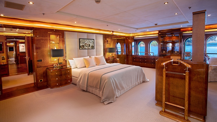 Owner's Suite bedroom on Aqua Mare Galapagos superyacht, with double bed, ample floorspace, accent lights & veneer furniture.