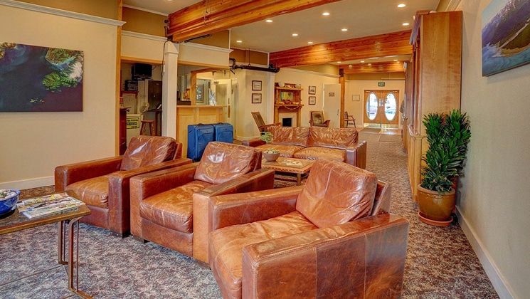 Lobby at Land's End Resort Alaska with leather chairs, coffee table, beige & wood accents, front desk & open concept.