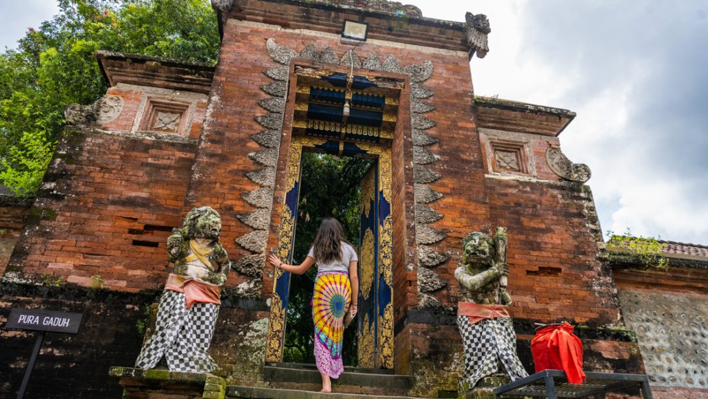 Woman in colorful skirt enters religious site of Lingsar, a place where Hindus, Muslims & Buddhists worship in Lombok, Indonesia.