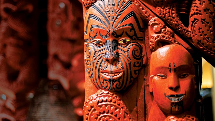 a bright red Maori mask depicting a face with black paint