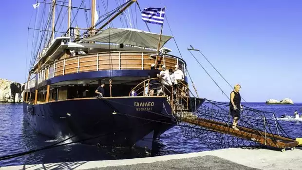 The small sail ship the Galileo docked with travelers disembarking off the boat in the Greek Isles.