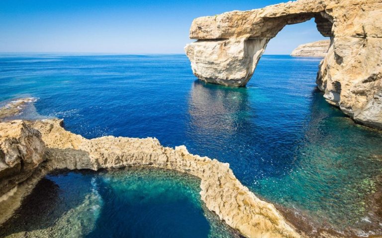 The cliffs and arches at Gozo seen on a sunny day with clear, bright blue water