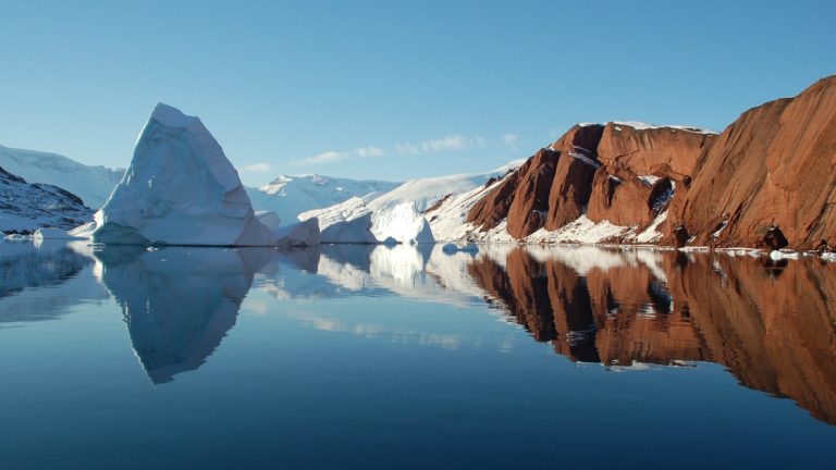 Seen from a luxury greenland cruise, Scoresby Sound, the largest fjord in the world. Jagged formations of red rock and white ice.