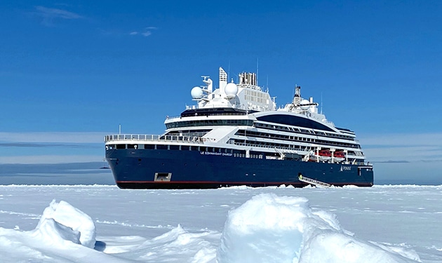 Parked in sea ice at the North Pole is the luxury icebreaker le commandant Charcot. Dark blue hull with white multi level decks.