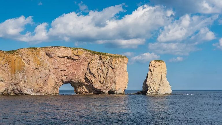 Perce's beige rocky outcrop with arch & detached islet over the sea, seen on small boat cruises on the St. Lawrence River.