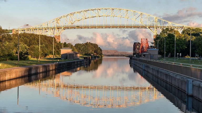 Yellow draw bridge over glassy canal at sunset in Saul St. Marie, Ontario, Canada, seen on small ship greast lakes cruises.