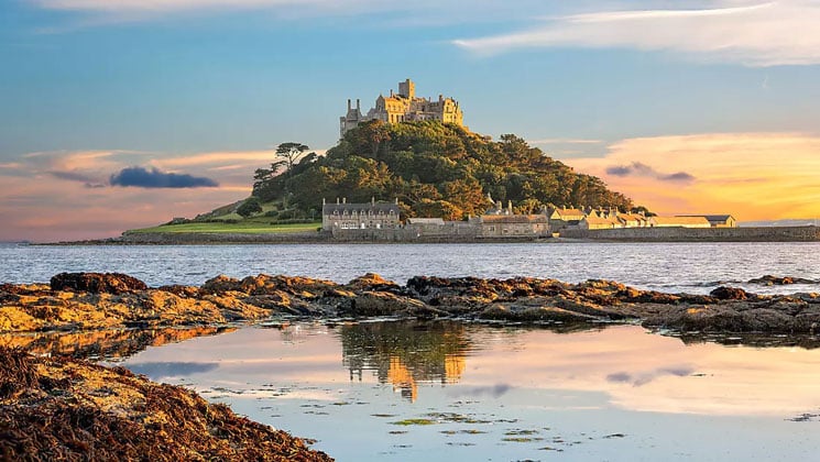 Castle sits atop an island's mountain at sunset on the Treasures of Ireland & The British Isles trip.