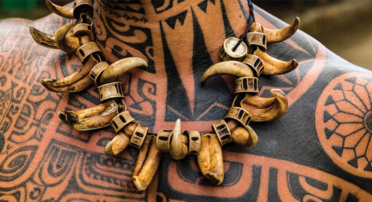 Close up of man's neckline with tribal tattoos & a necklace made of bone & shell, seen on an Ancient Polynesia small ship cruise.