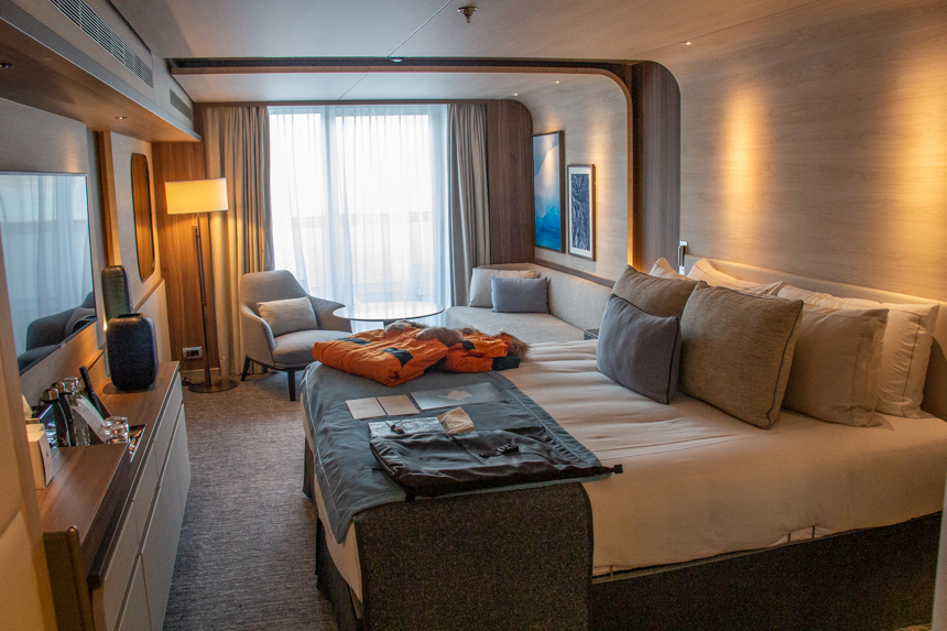 Deluxe Suite aboard Le commandant Charcot polar luxury ice breaker. Private balcony, small seating area, TV and bathroom.