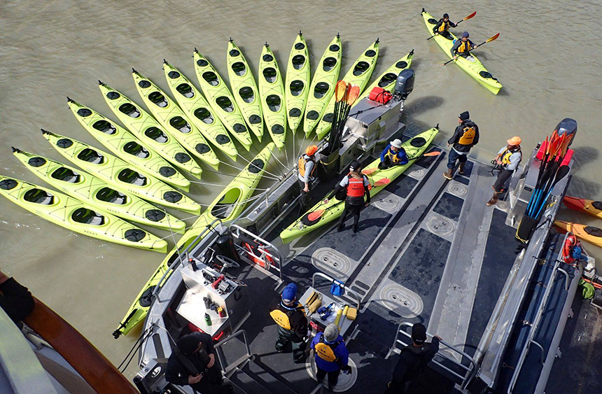 15 lime green double kayaks are tied to 
a custom aluminum platform called the Sea Dragon used for kayak activity aboard UnCruise trips.
