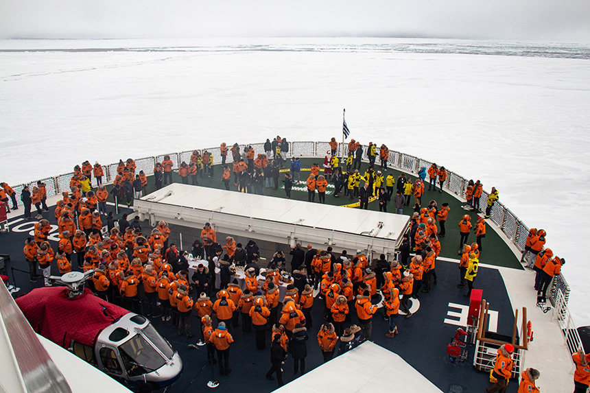 White ice for miles, Guests in orange parkas gather on the ship bow to celebrate reaching 90 degrees north.