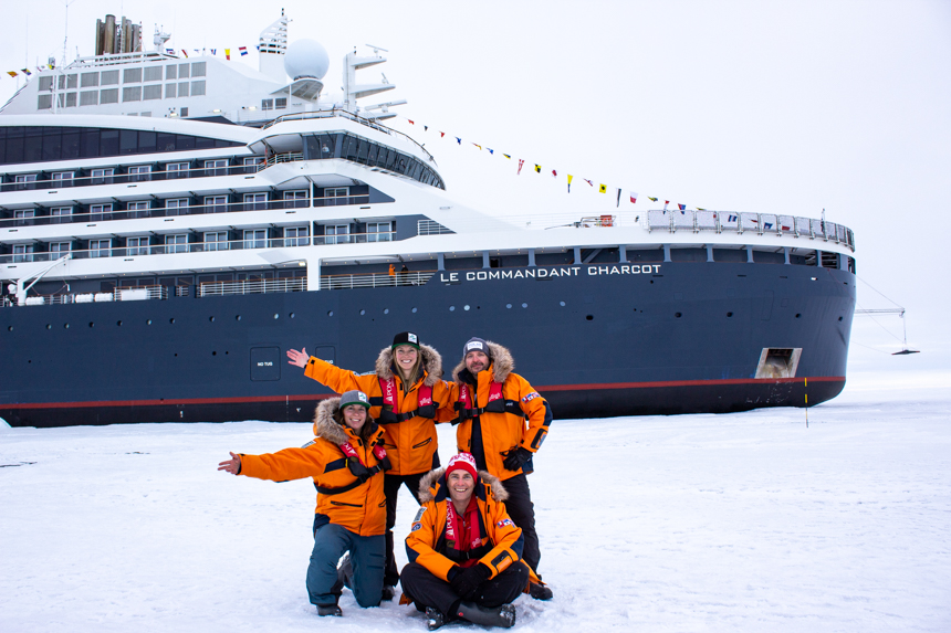Group of travelers pose at North Pole in front of Le Commandant Charcot luxury icebreaker ship