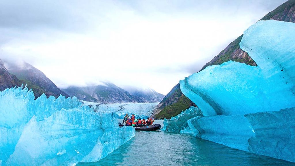 Black Zodiac sits in a tunnel of blue ice on a cloudy day of the Wild Alaska Escape: Glaciers of Prince William Sound cruise.